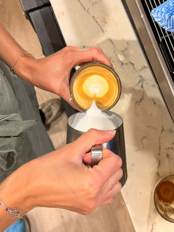 Barista pouring latte art at L'Anse French Café